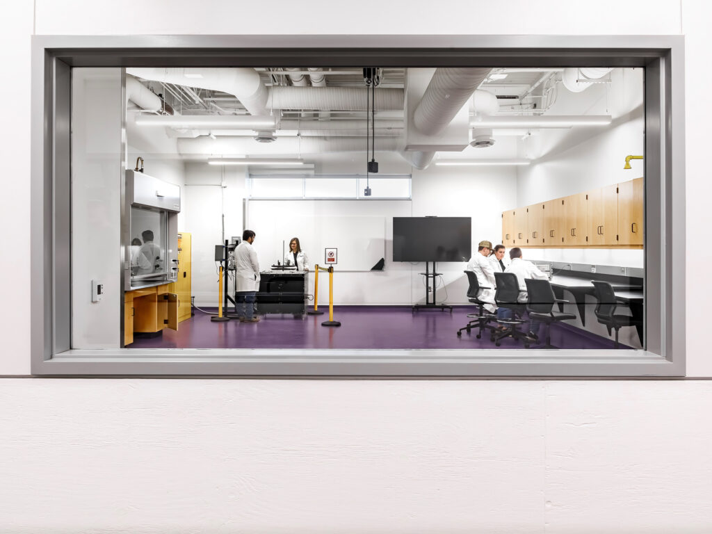 A view of the ACU Nuclear Science & Engineering Center lab room through a window, showcasing scientific equipment and workspace.