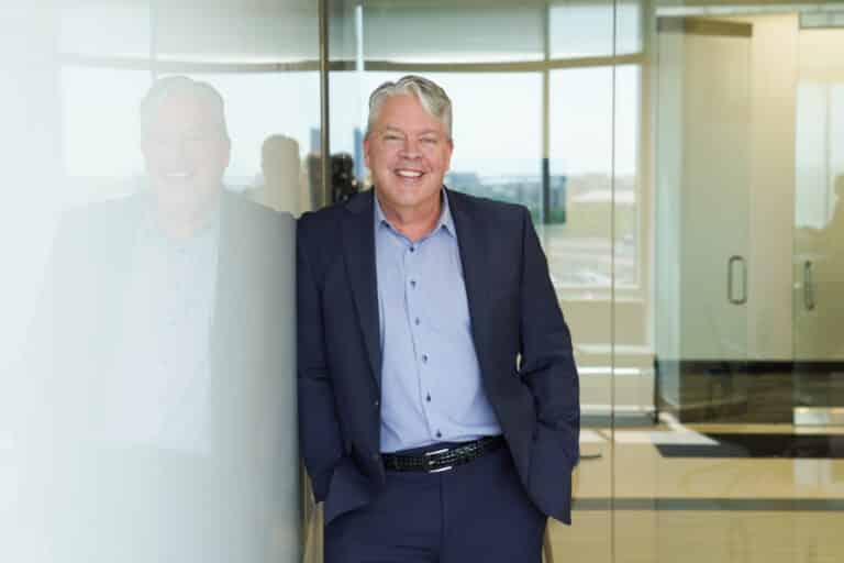 Man leaning against a glass wall for a professional business portrait