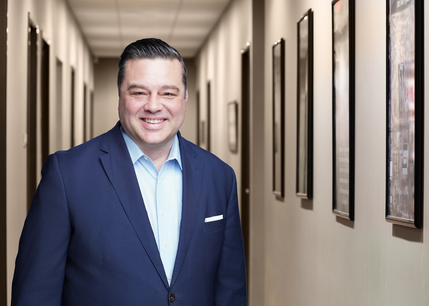 headshot of James Howard in a long hallway with frames