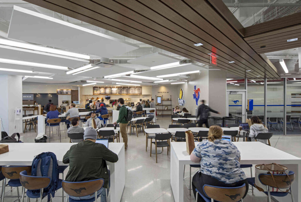 Interior of a modern university cafe with people seated at tables and ordering food.